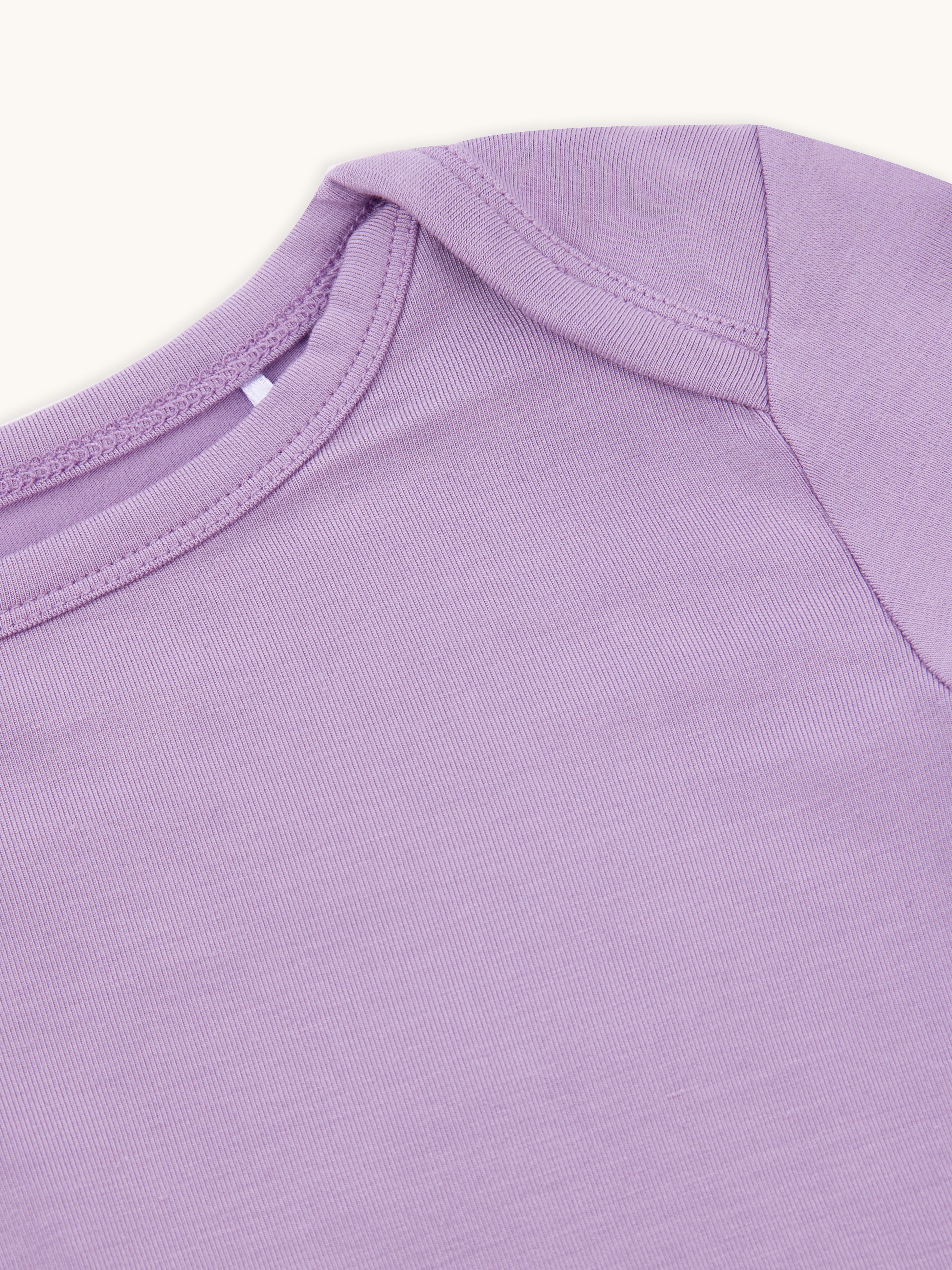 Close-up of the right side of the neck and shoulder of a lilac kid's t-shirt.