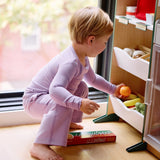 Girl playing with toy fruits while wearing a long sleeve kid's t-shirt and straight pant bundle in lilac