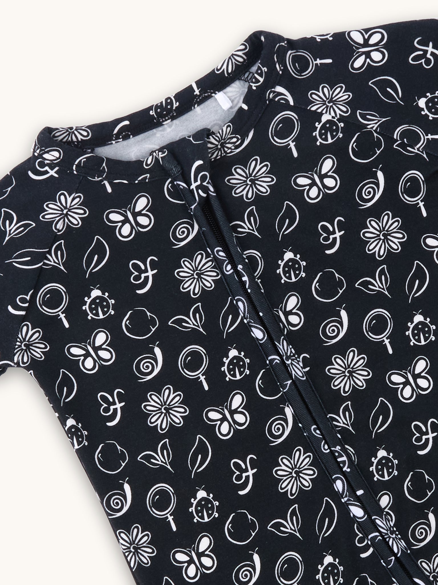 farren nido onseie zipper sleeper black closeup of white details of butterfly flowers and snails