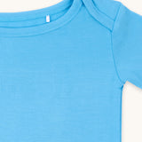 Zoomed-in view of the neckline and shoulder of a cornflower blue t-shirt.