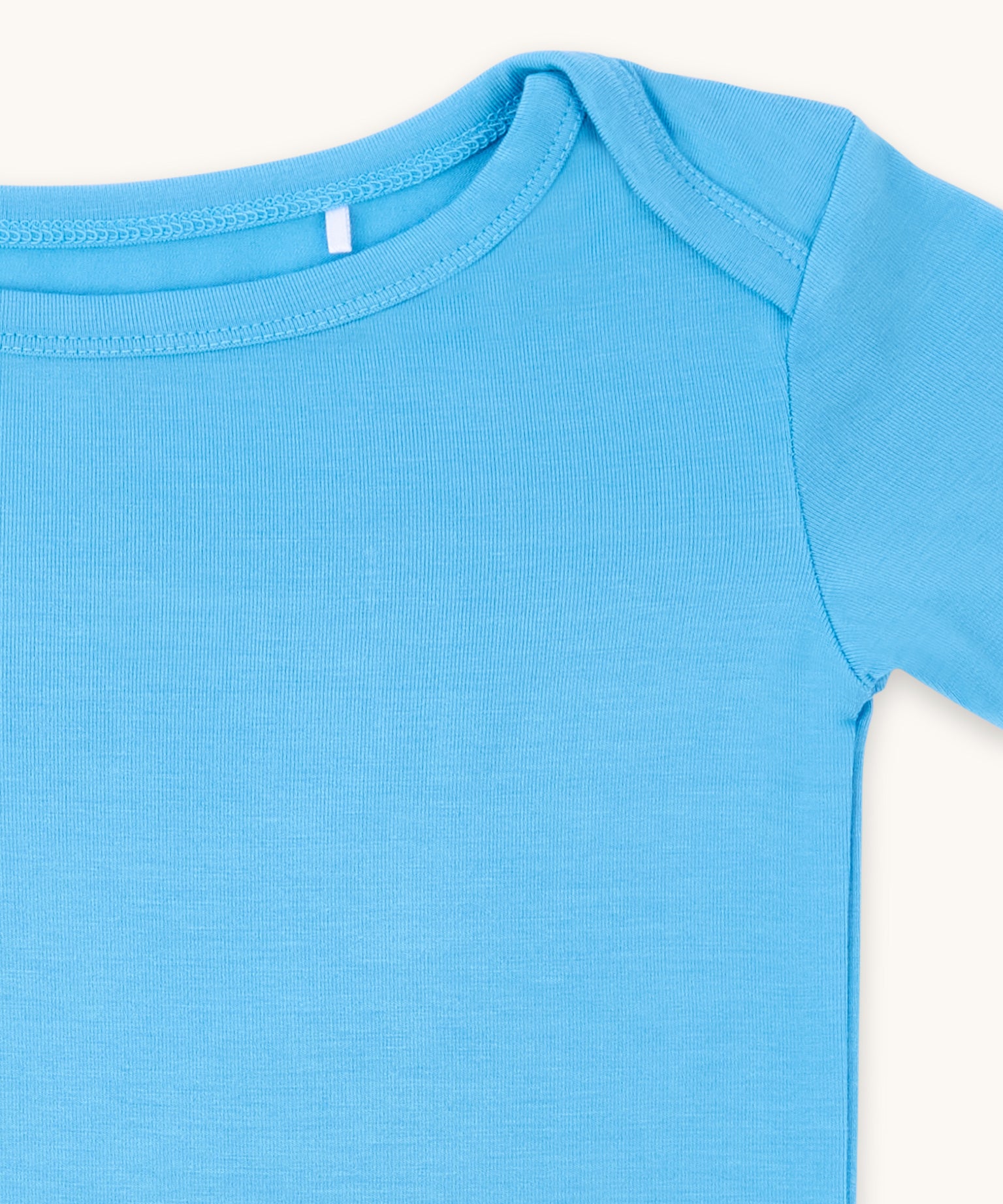 Zoomed-in view of the neckline and shoulder of a cornflower blue t-shirt.