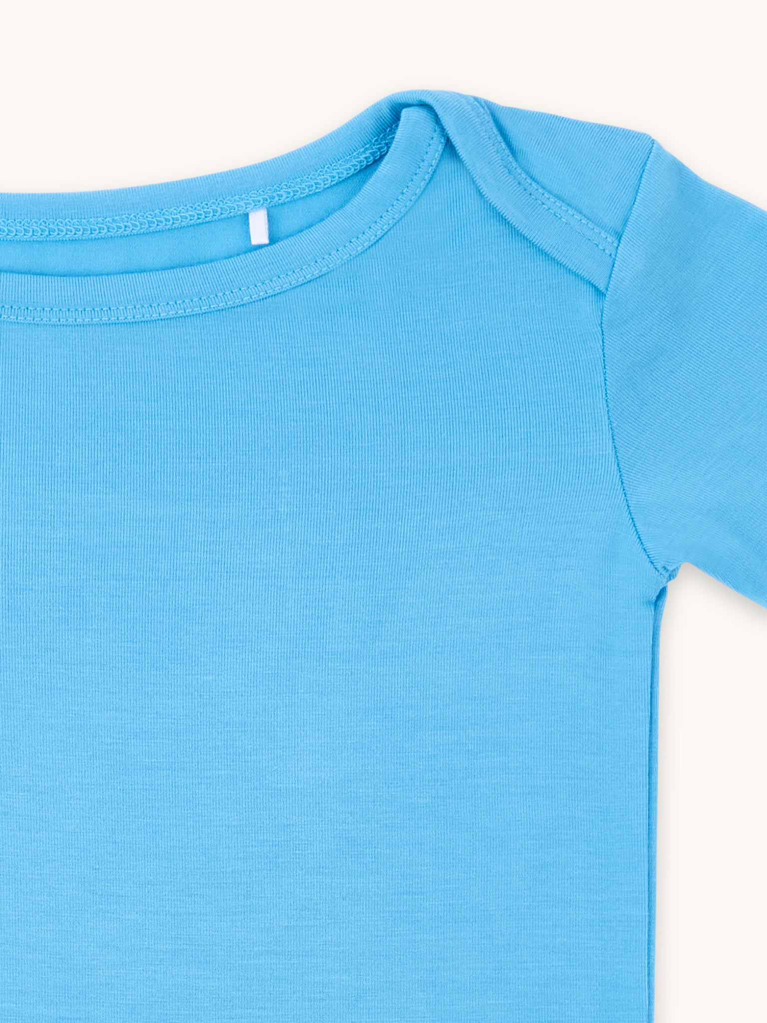 Zoomed-in view of the neckline and shoulder of a cornflower blue t-shirt.